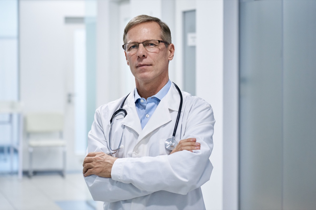 Medical doctor stands arm crossed in hospital.