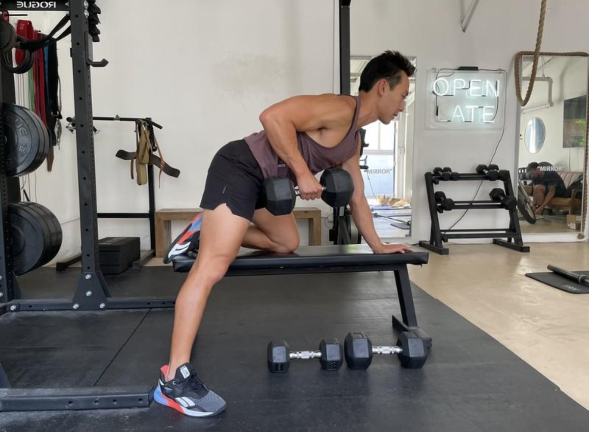 trainer doing dumbbell row exercise