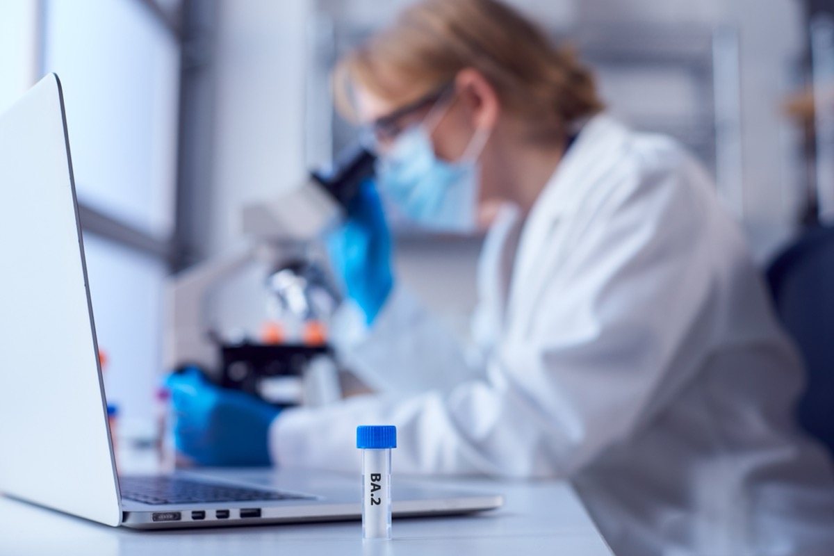 Female Lab Research Worker Wearing PPE Holding Test Tube Labelled BA.2