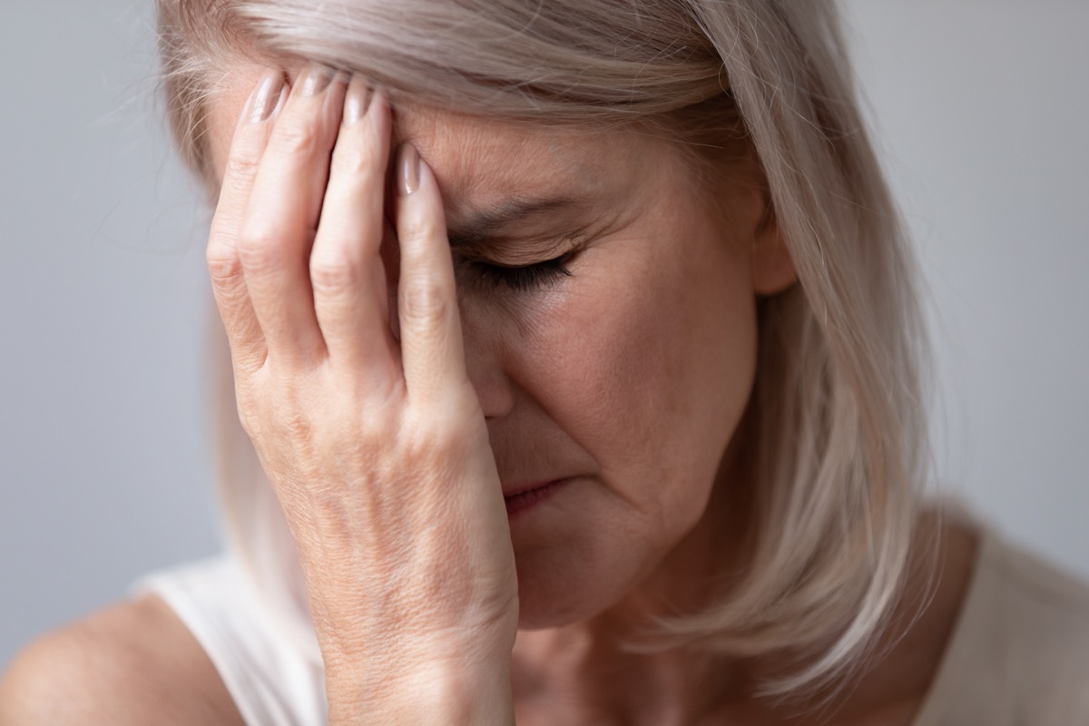 Close up head shot portrait unhealthy middle aged woman touching forehead. Unhappy sad mature female retiree feeling tired, suffering from head ache, migraine or dizziness, healthcare concept.