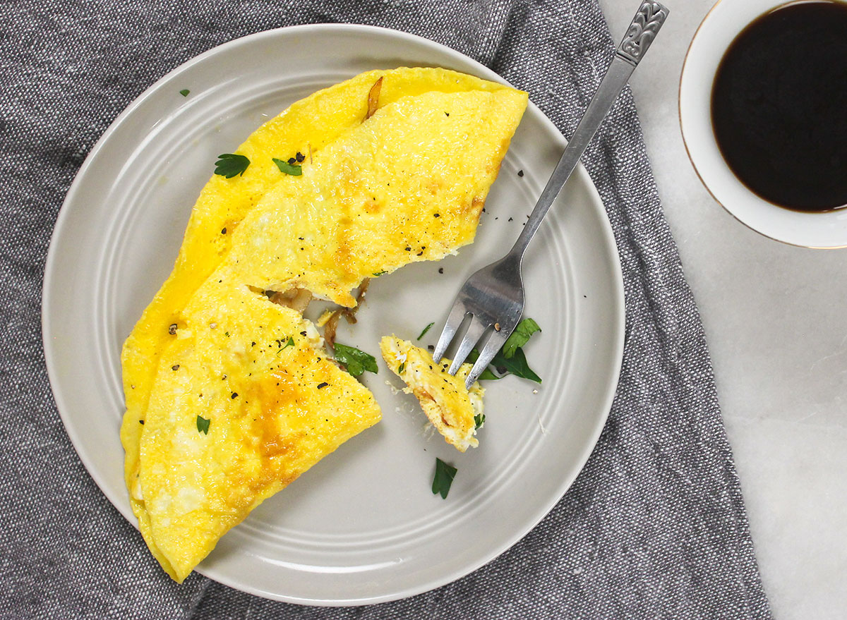 breaking into a cooked omelet on a grey plate