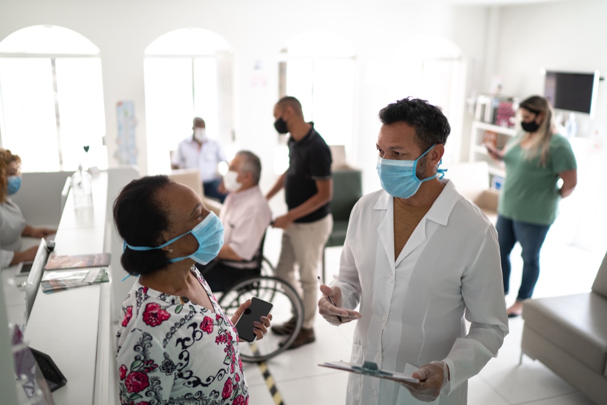 Patient arriving at medical clinic and being called by the doctor using face mask.