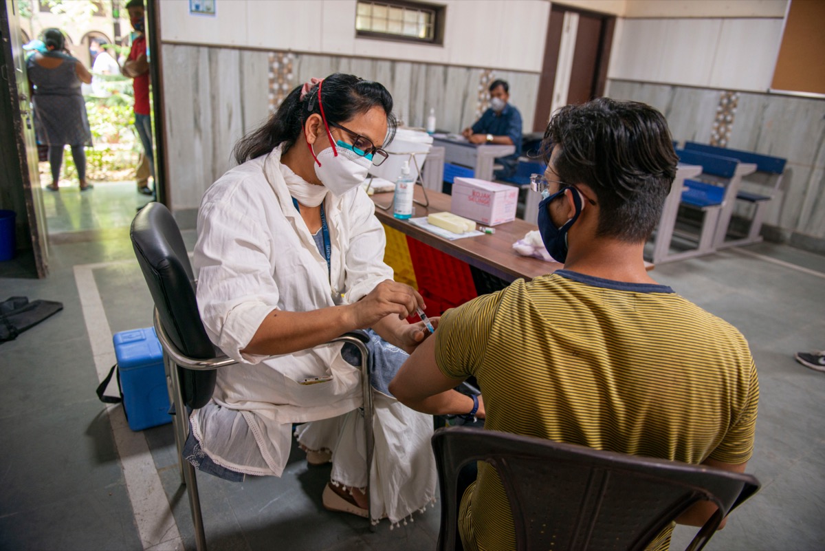 Man being vaccinated by a nurse in an Indian's mass vaccination site.