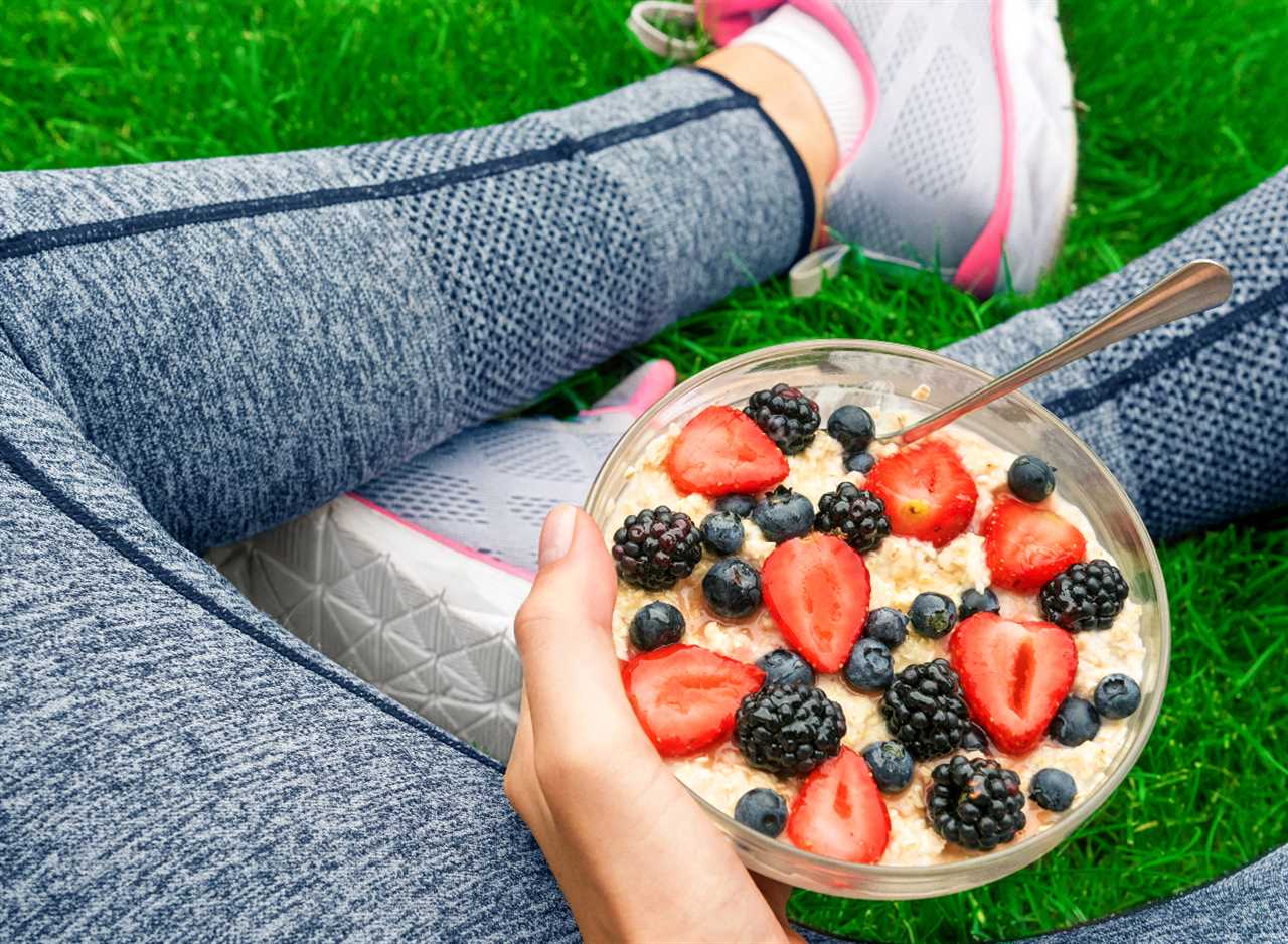 female runner sits on grass while eating berries with oatmeal