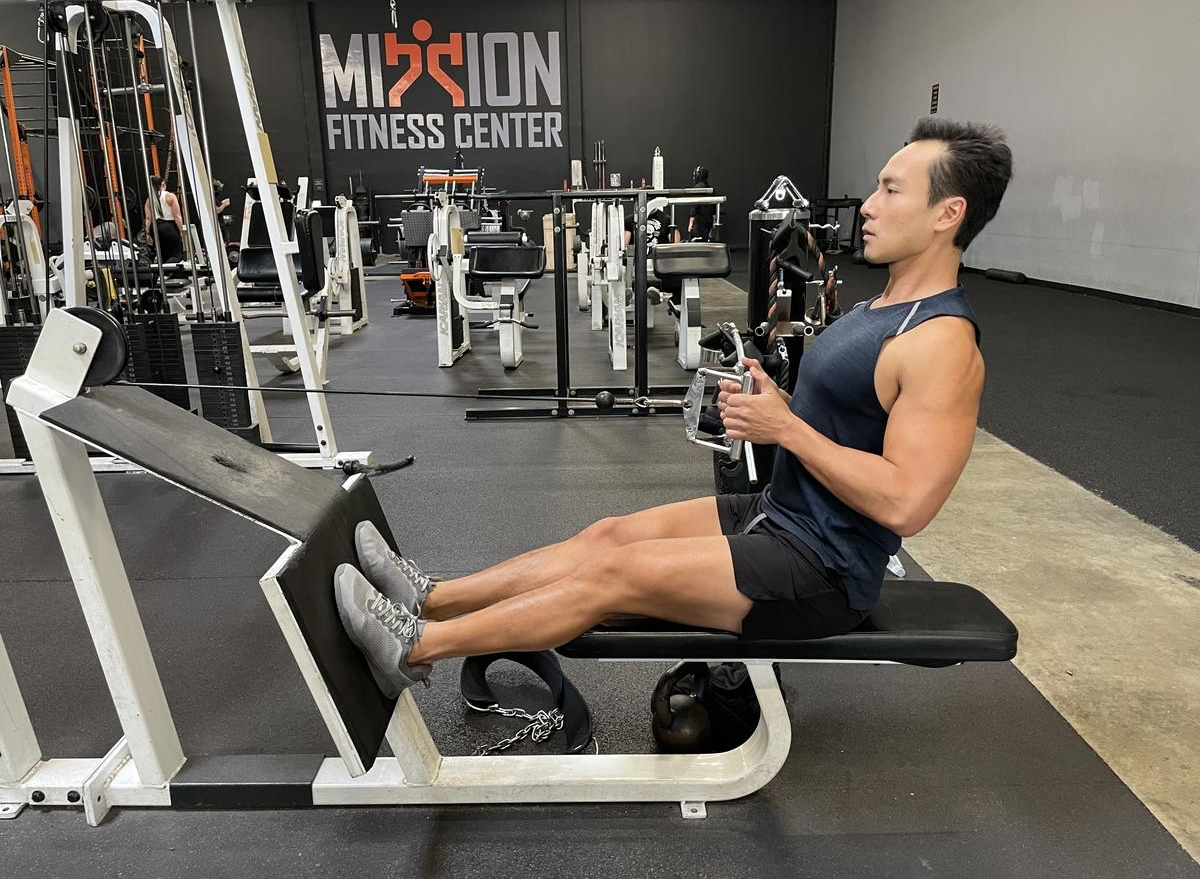 trainer demonstrating seated row to lose your gut in your 40s