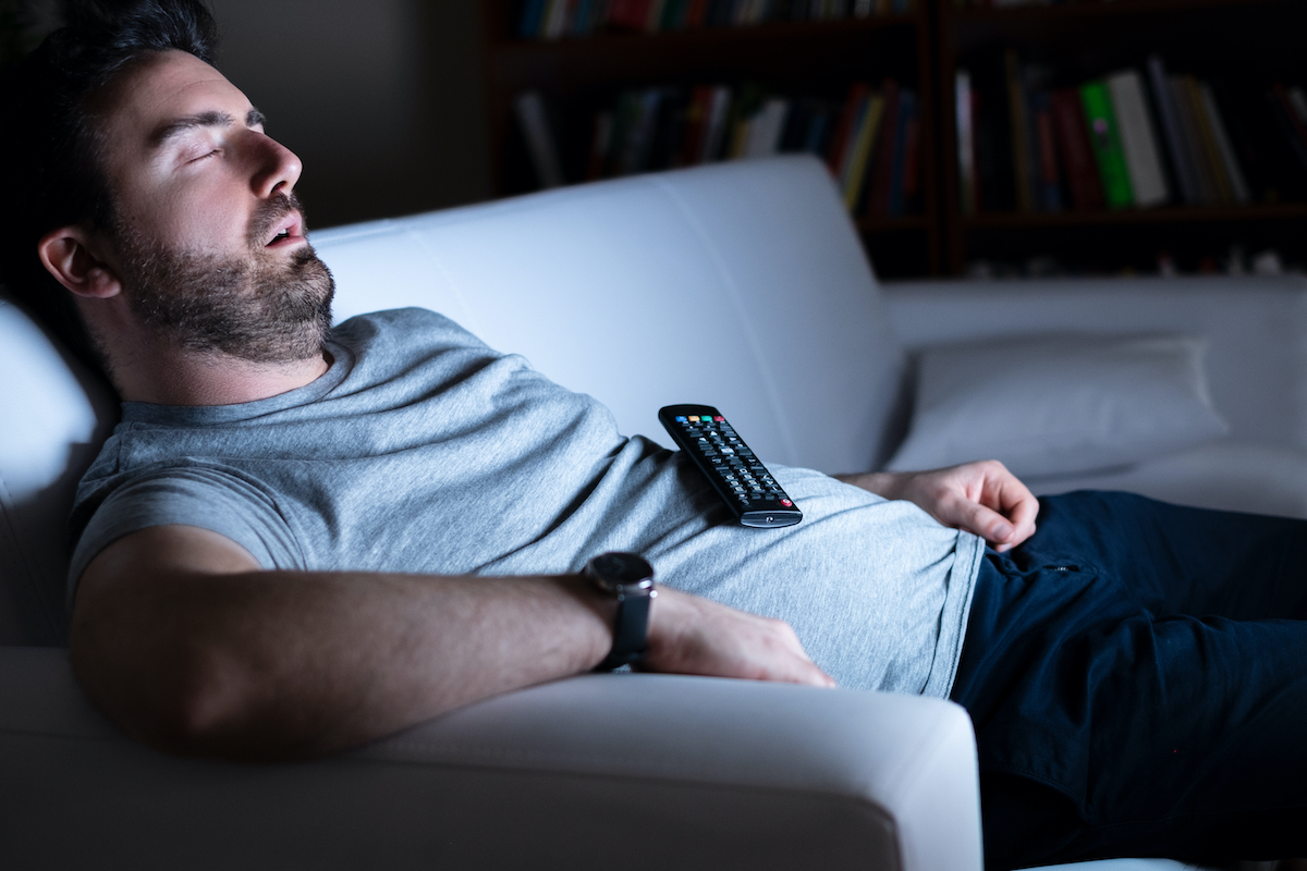 Lazy man watching television at night alone
