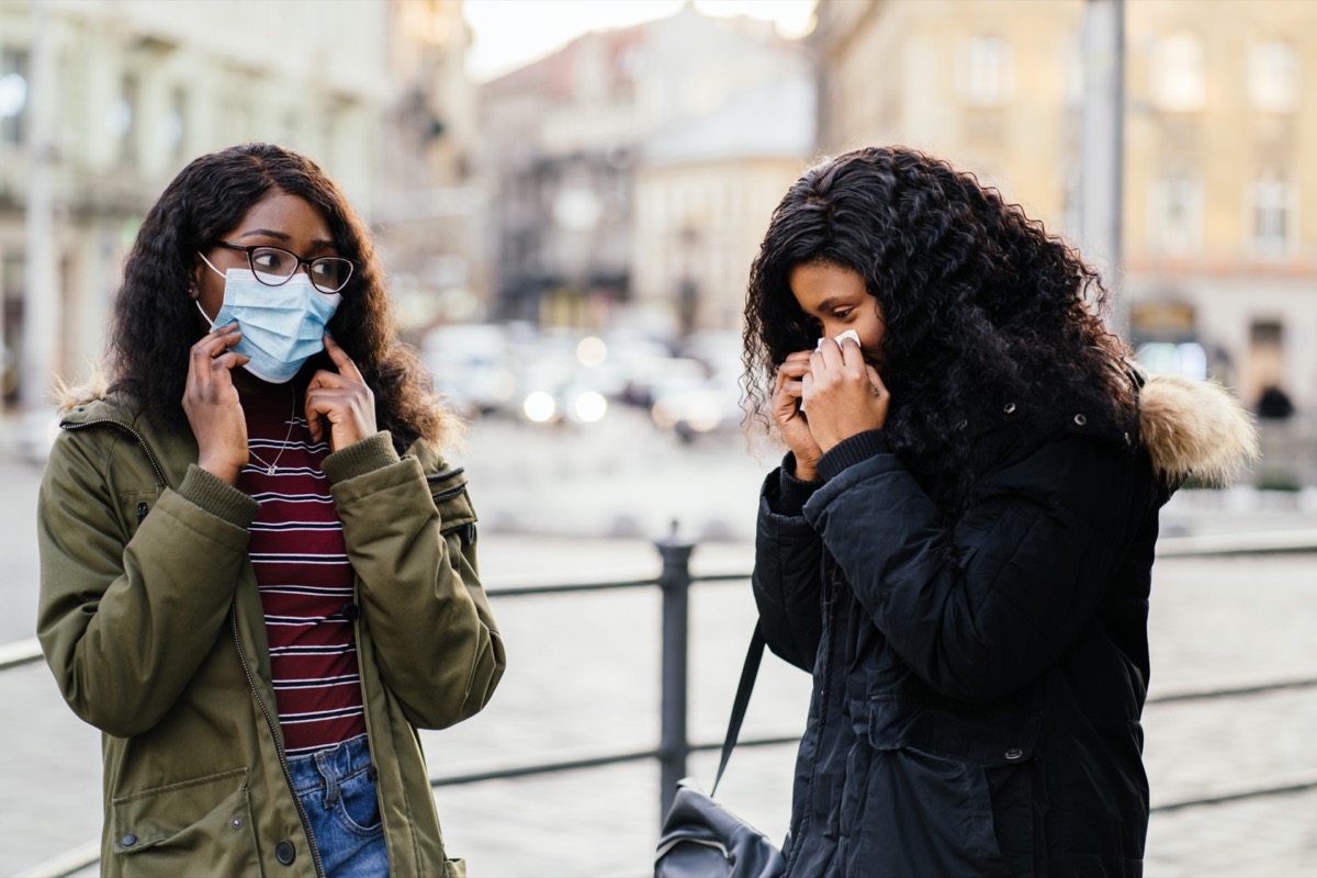 with sneezing at city street, woman without protective mask while spreading flu,cold, Covid-19
