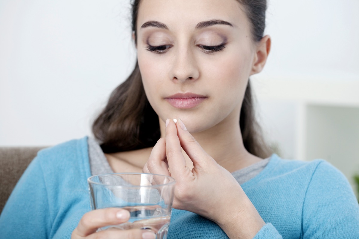 Woman holding a pill in her hand.