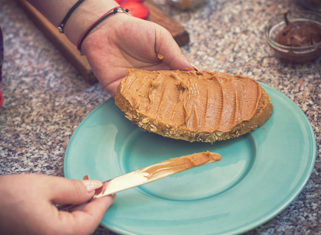 Woman spreading peanut butter on bread