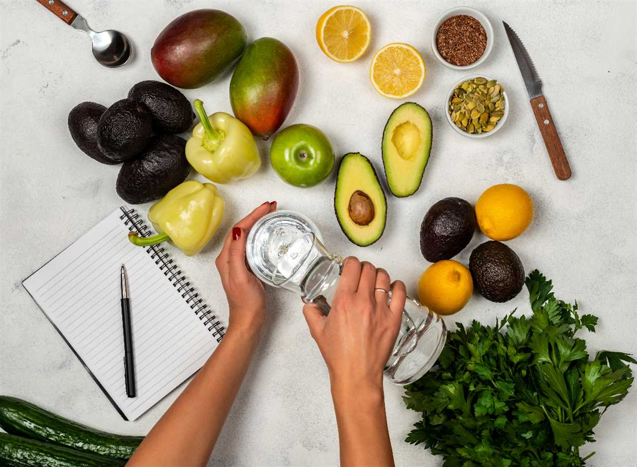 woman pouring water into glass surrounded by fruits, vegetables, nuts, seeds, and notebook