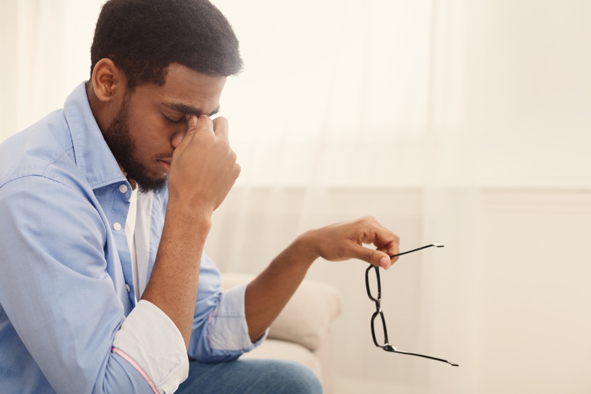 man massaging nose bridge, taking glasses off, having blurry vision or dizziness