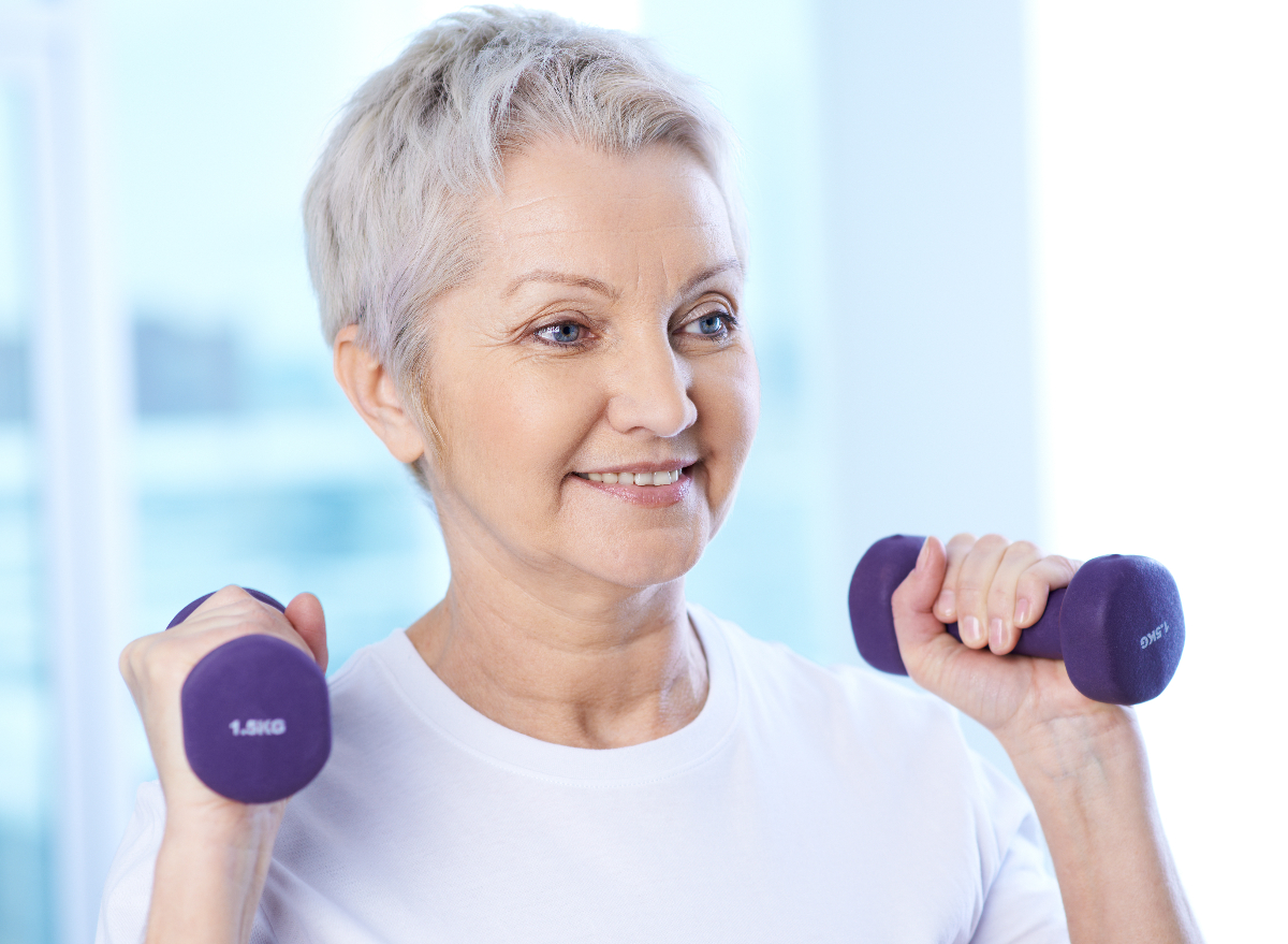 woman demonstrates how to lose face fat with resistance training, lifting dumbbells