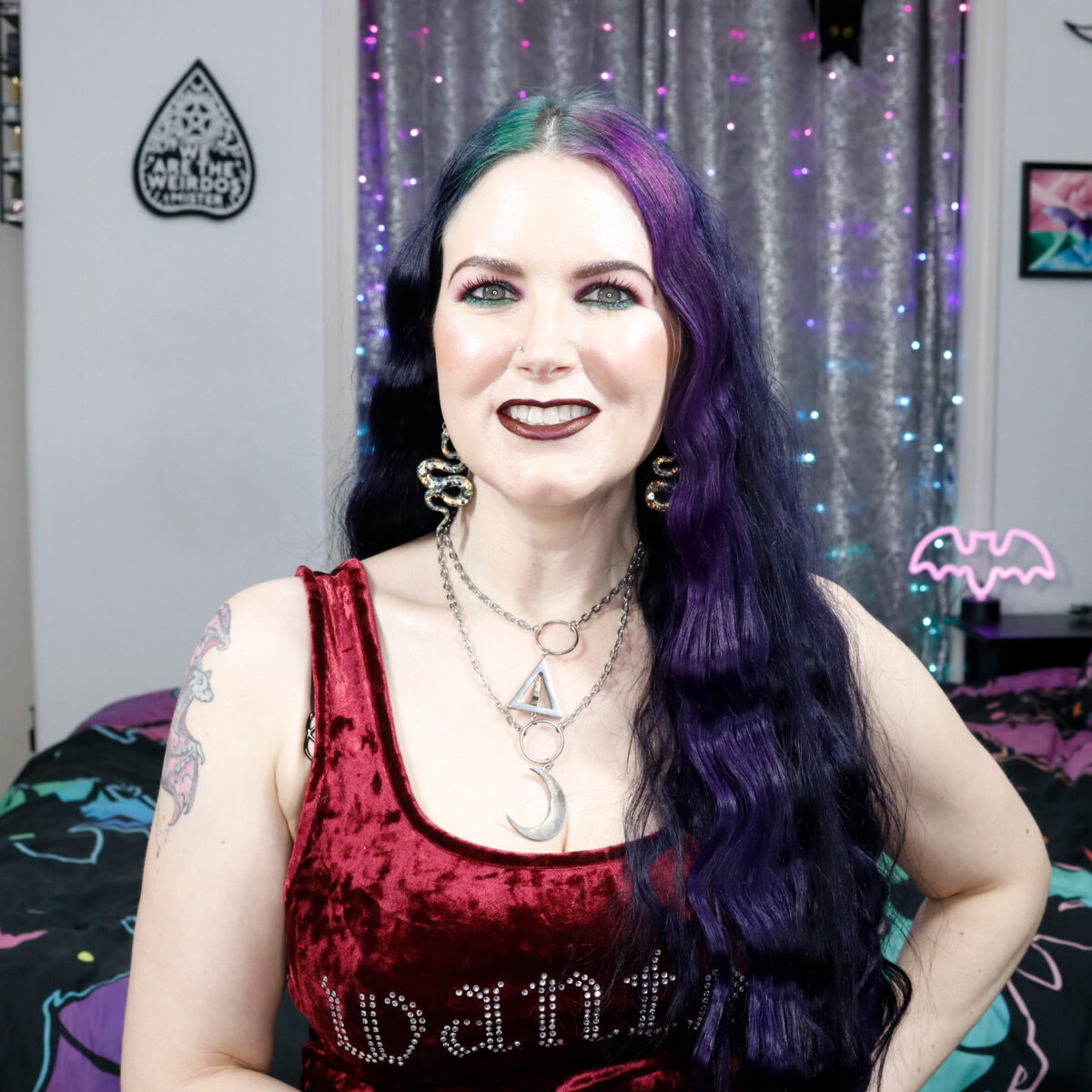 Cordelia is wearing a red crushed velvet crop top and witch necklace