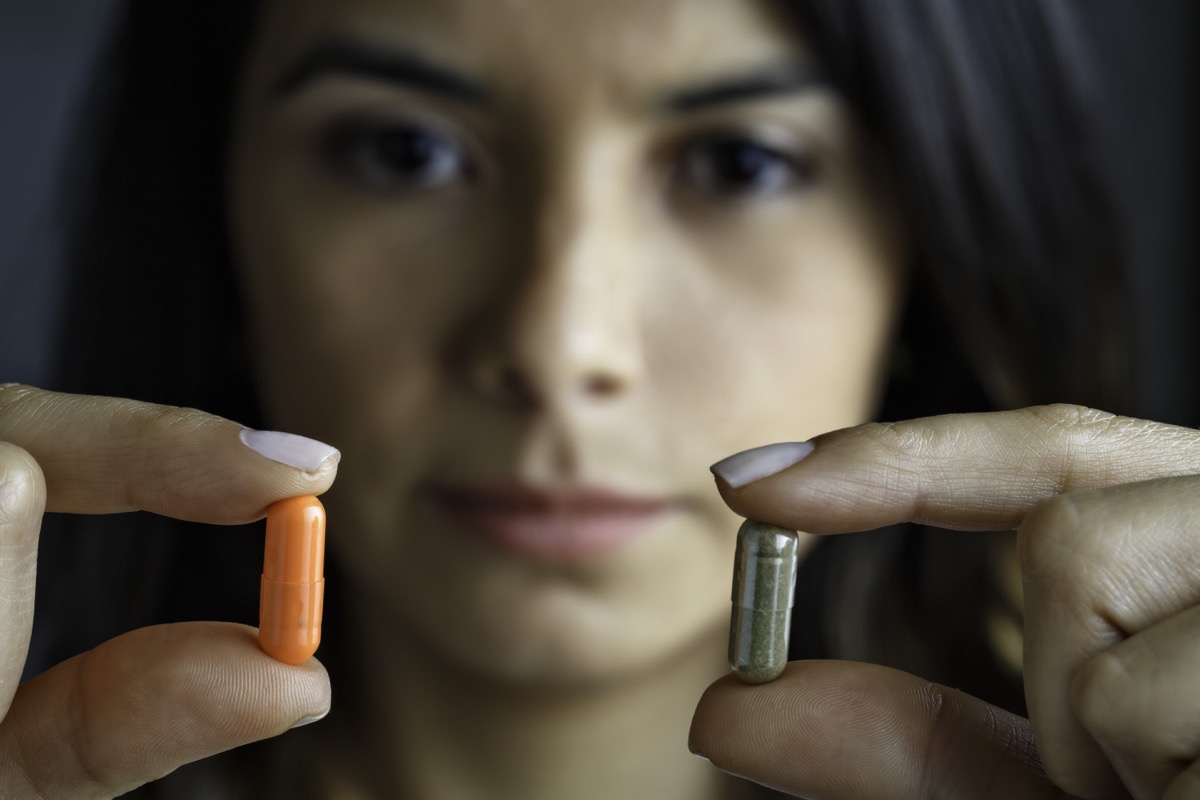 Young Hispanic woman choosing between antibiotics or alternative medicine.