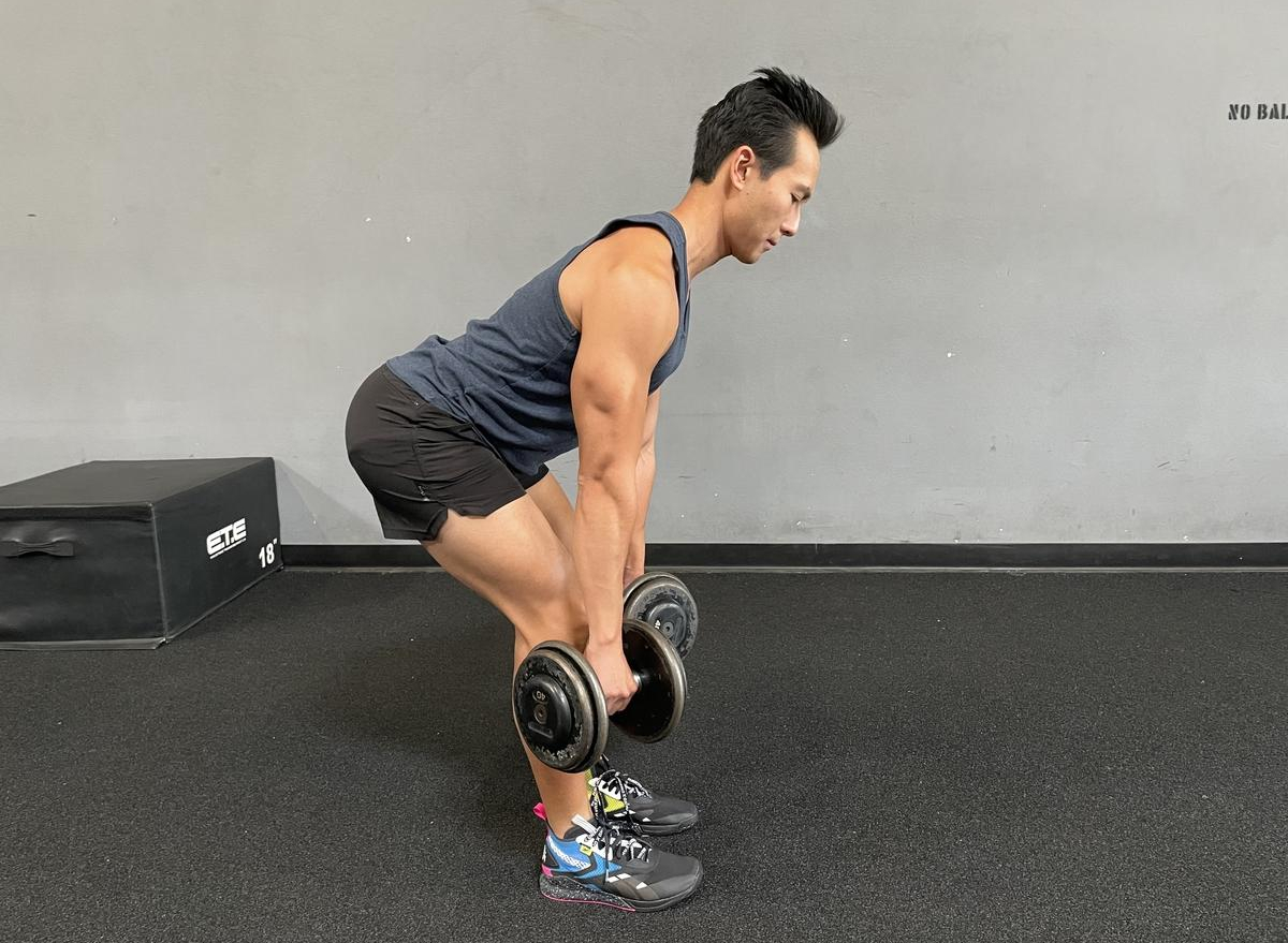 trainer demonstrating dumbbell romanian deadlift to reverse aging