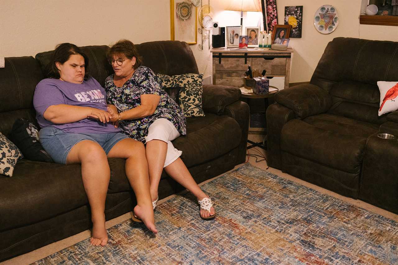 Wanda Felty sits with her daughter Kayla in their home in Norman, Okla., on July 19, 2022. Kayla's brain did not fully form in utero; she is mostly non-verbal and has significant visual impairment, among other medical issues. Felty and her husband are Kayla's primary caretakers. 