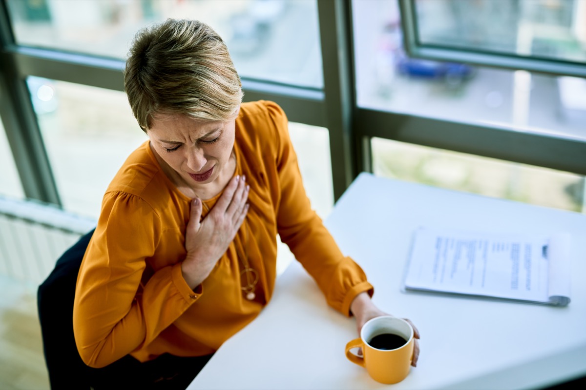 Businesswoman coughing while having coffee break in the office.