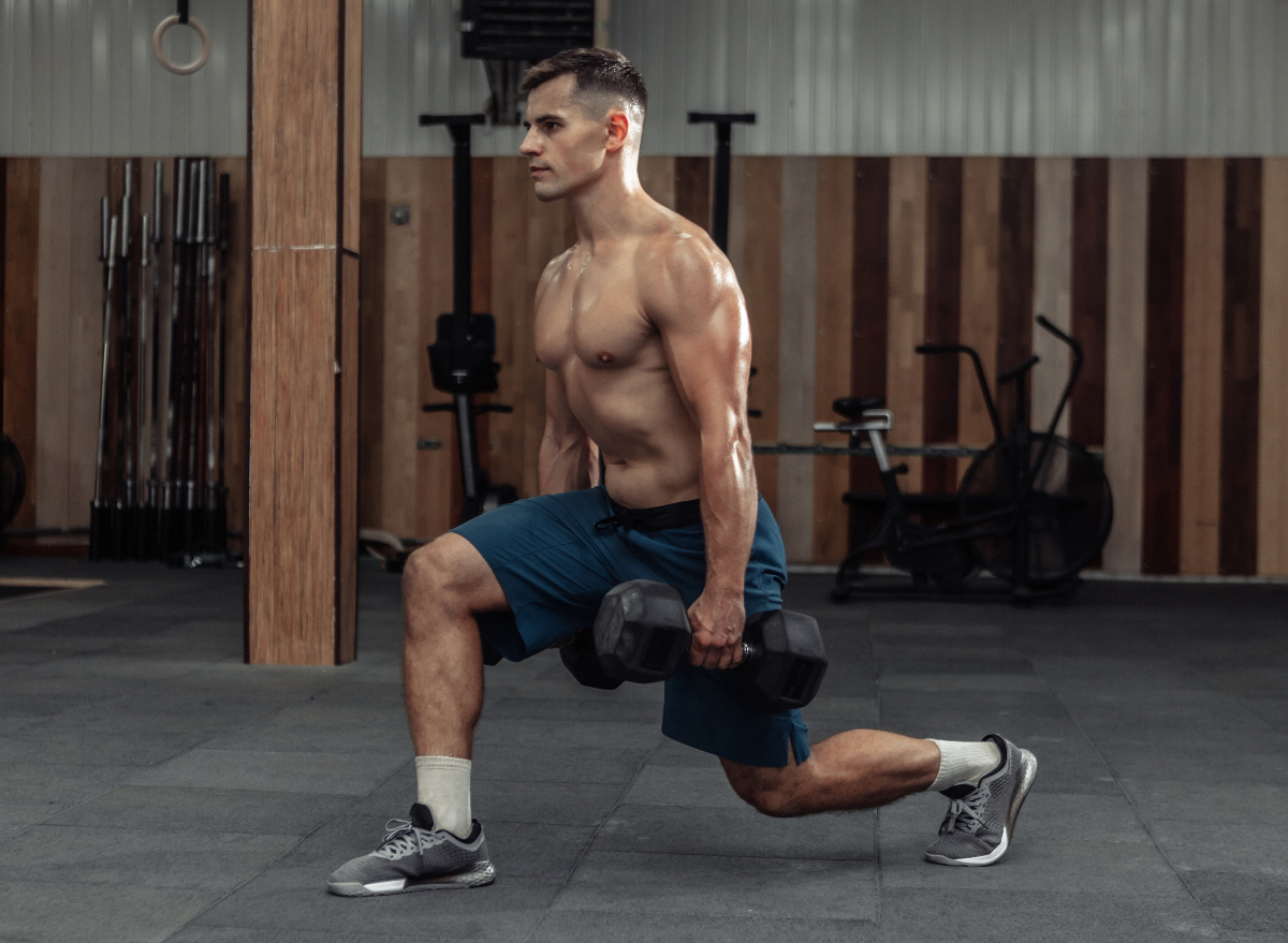 man doing dumbbell exercises, reverse lunges at the gym