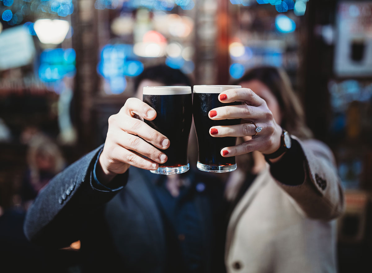 man and woman holding up glasses of dark beer guinness