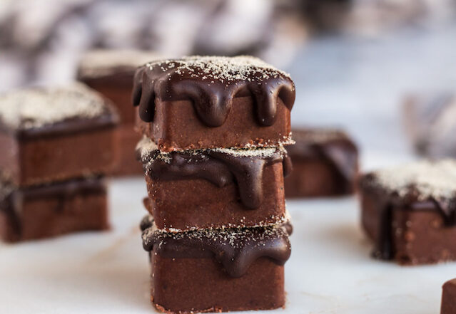 Three chocolate squares topped with dripping chocolate in a stack.