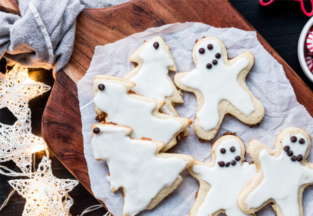 Plate with frosted sugar cookies shaped like pine trees and ghosts.