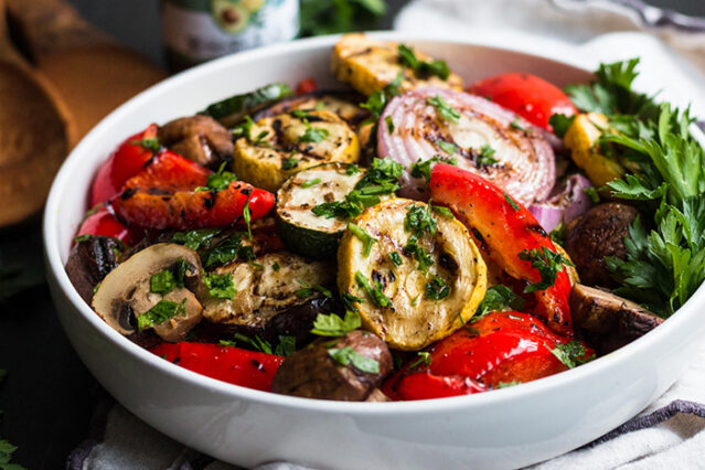 White serving bowl loaded with colorful mixed grilled vegetables.