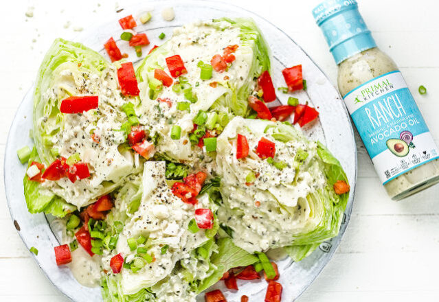 White serving platter with wedge salad garnished with bright red diced pepper and a bottle of Primal Kitchen Ranch Dressing.