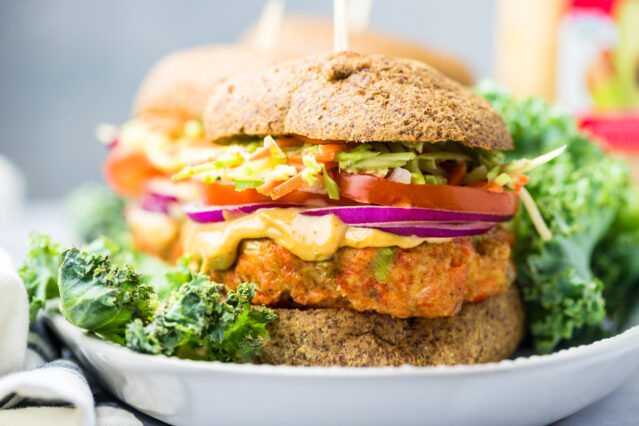 Salmon burger on white plate with lettuce.