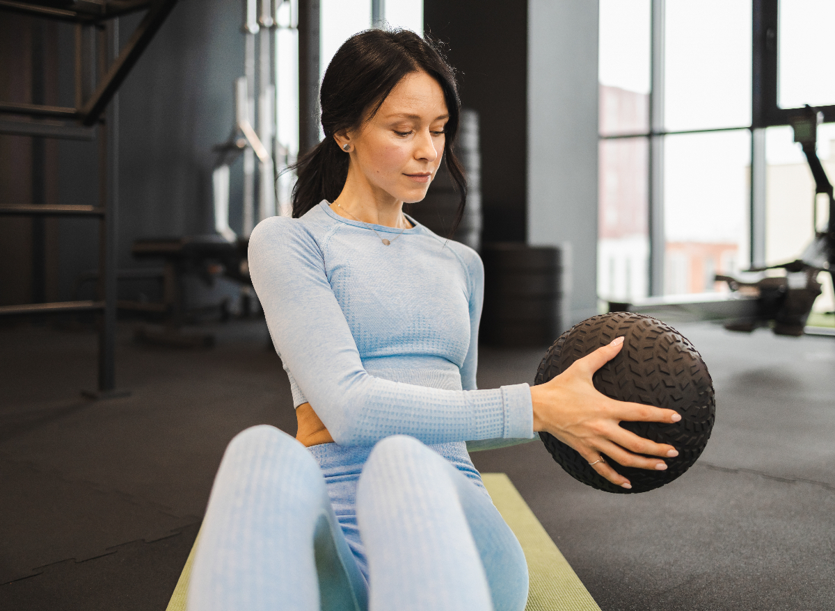 woman doing russian twists with medicine ball, concept of exercises for a slimmer core in 30 days