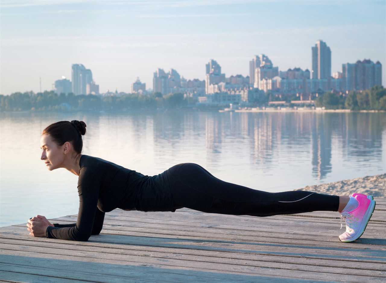 woman doing planks on a pier by the water next to city, concept of strength exercises to drop 10 pounds in a month
