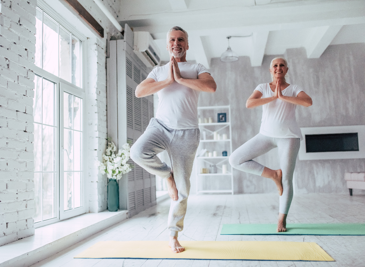 senior couple doing balancing yoga exercises at home