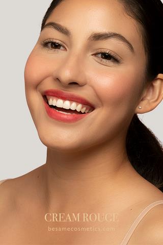 Young woman smiling wearing Bésame's Cream Rouge