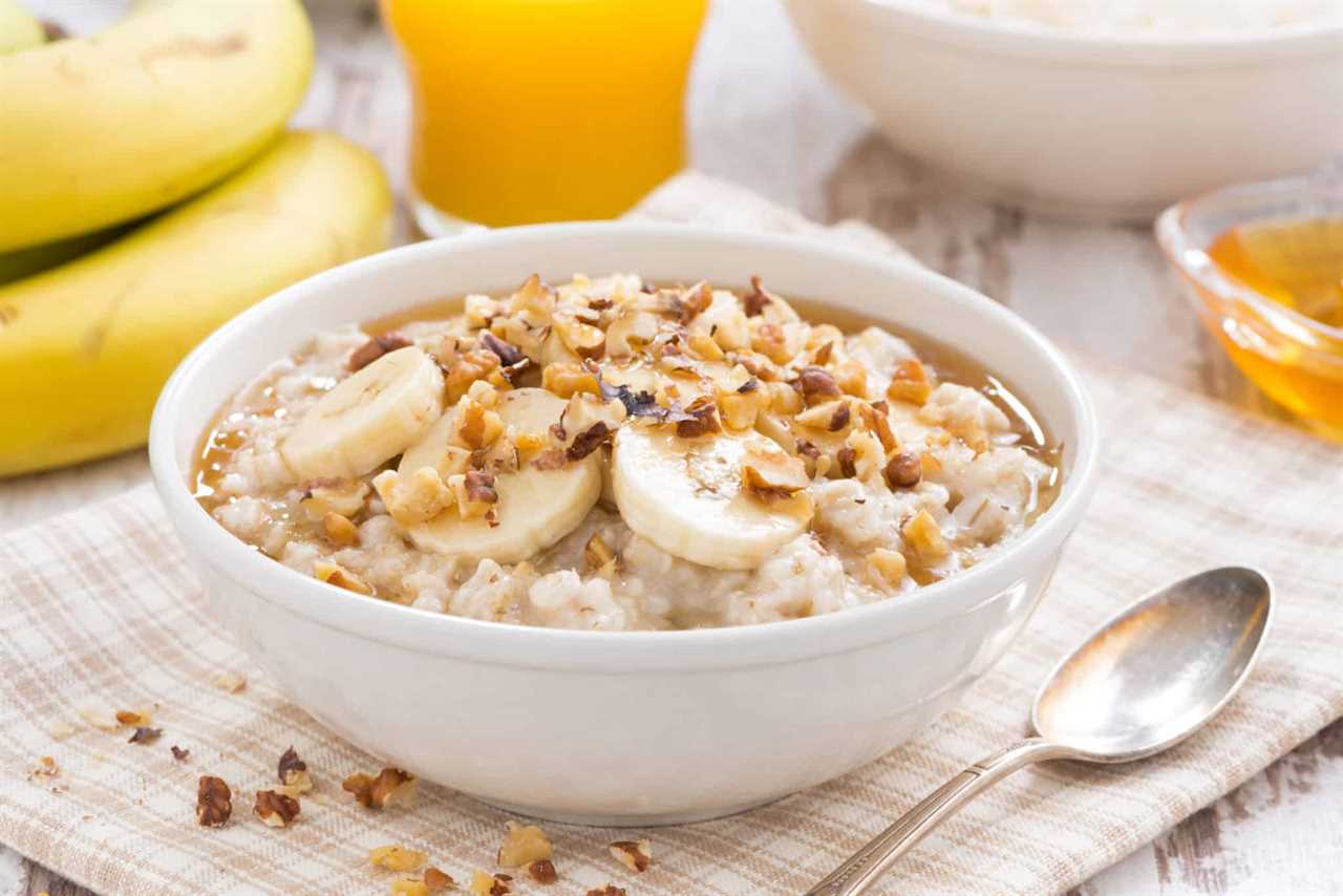 A bowl of oatmeal topped with granola and sliced bananas.