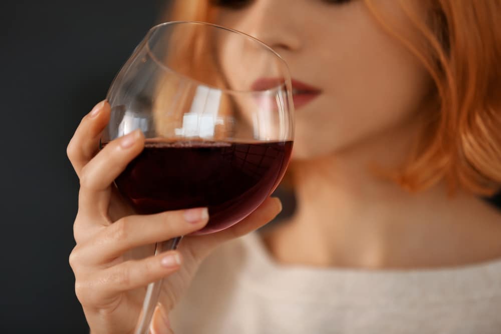 A woman drinking a glass of red wine.