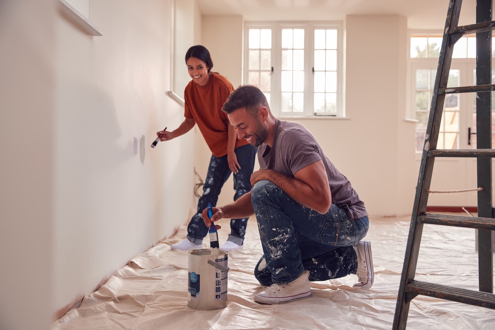 Couple painting the wall in their house.