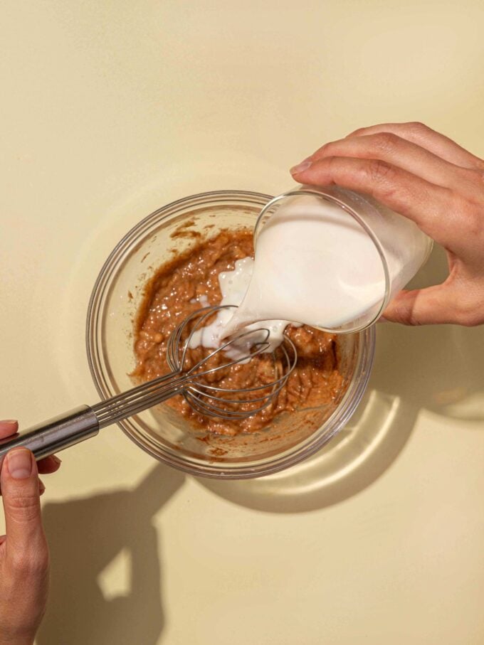 hand pouring milk into bowl