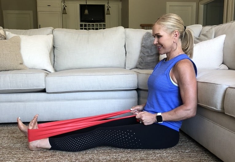 Chris Freytag sitting on floor stretching heel with resistance band