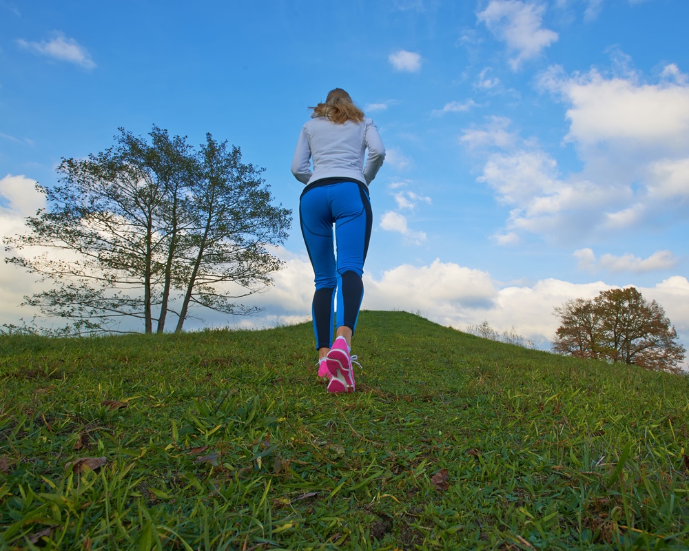 A woman walking up a grassy hill.