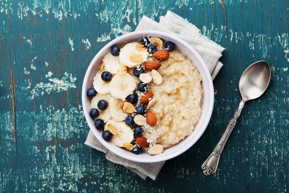 A bowl of oatmeal topped with blueberries, bananas, and nuts.