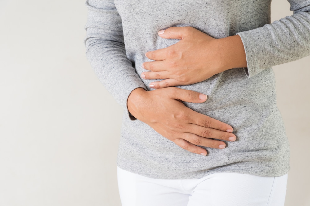 An uncomfrotable woman holding her stomach.