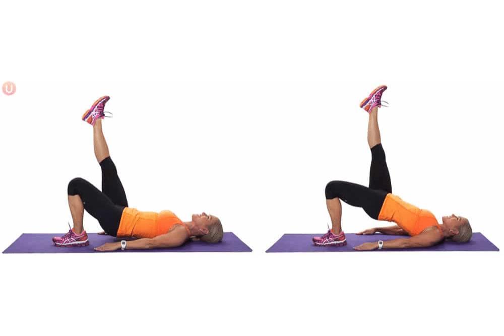 Chris Freytag demonstrating a single-leg hamstring bridge on a purple yoga mat.